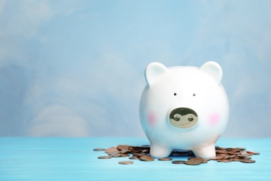 Photo of Cute piggy bank and coins on color table. Space for text