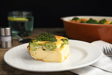 Photo of Tasty broccoli casserole served on wooden table, closeup
