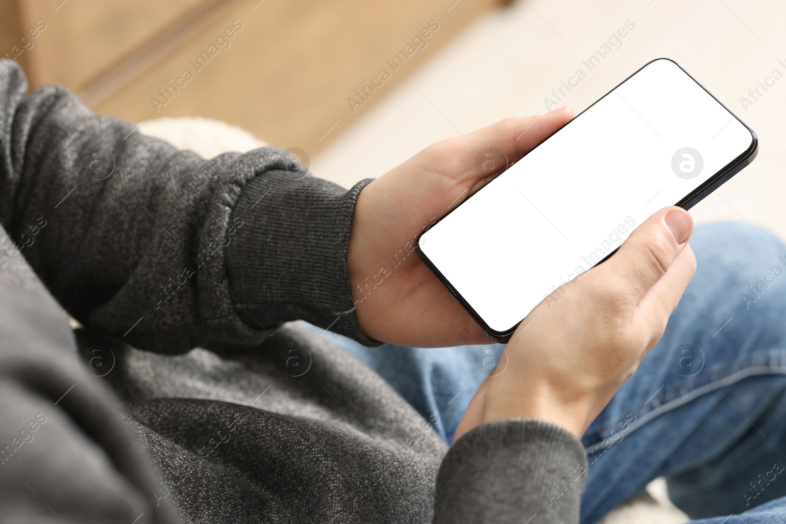 Photo of Man using smartphone with blank screen indoors, closeup. Mockup for design