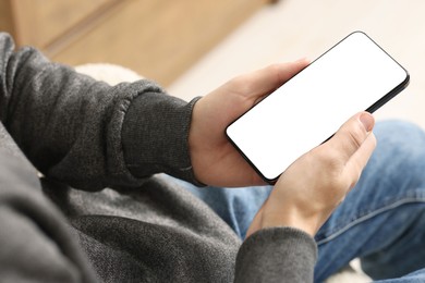 Photo of Man using smartphone with blank screen indoors, closeup. Mockup for design