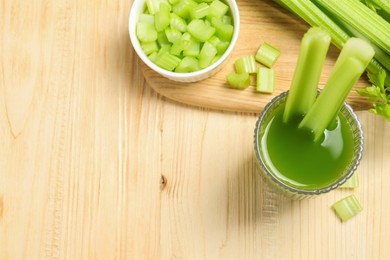 Glass of celery juice and fresh vegetables on wooden table, flat lay. Space for text