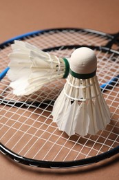 Photo of Feather badminton shuttlecocks and rackets on brown background, closeup