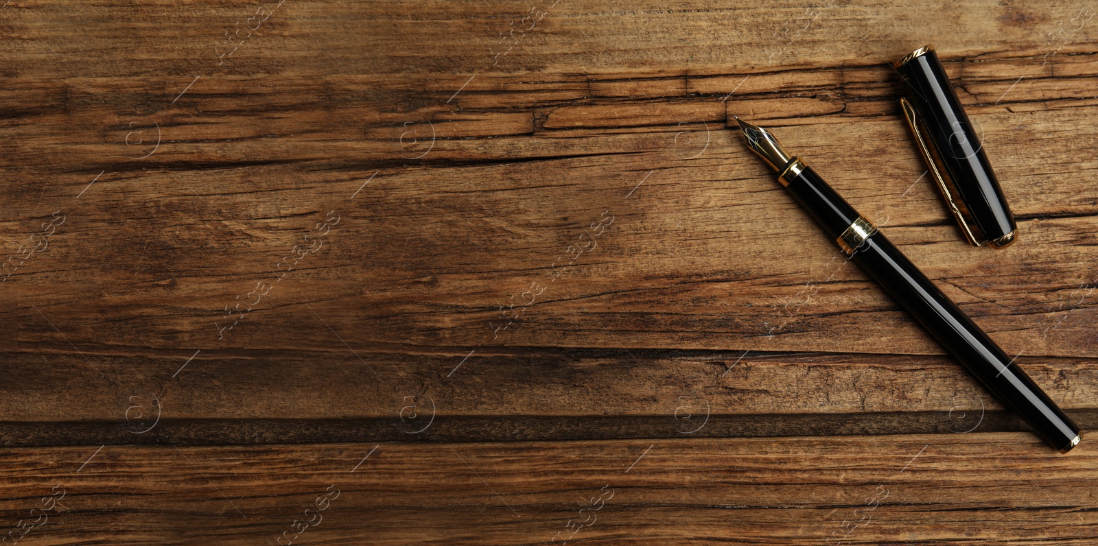 Image of Beautiful fountain pen on wooden table, top view with space for text. Banner design