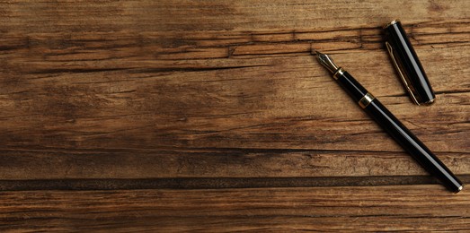 Image of Beautiful fountain pen on wooden table, top view with space for text. Banner design