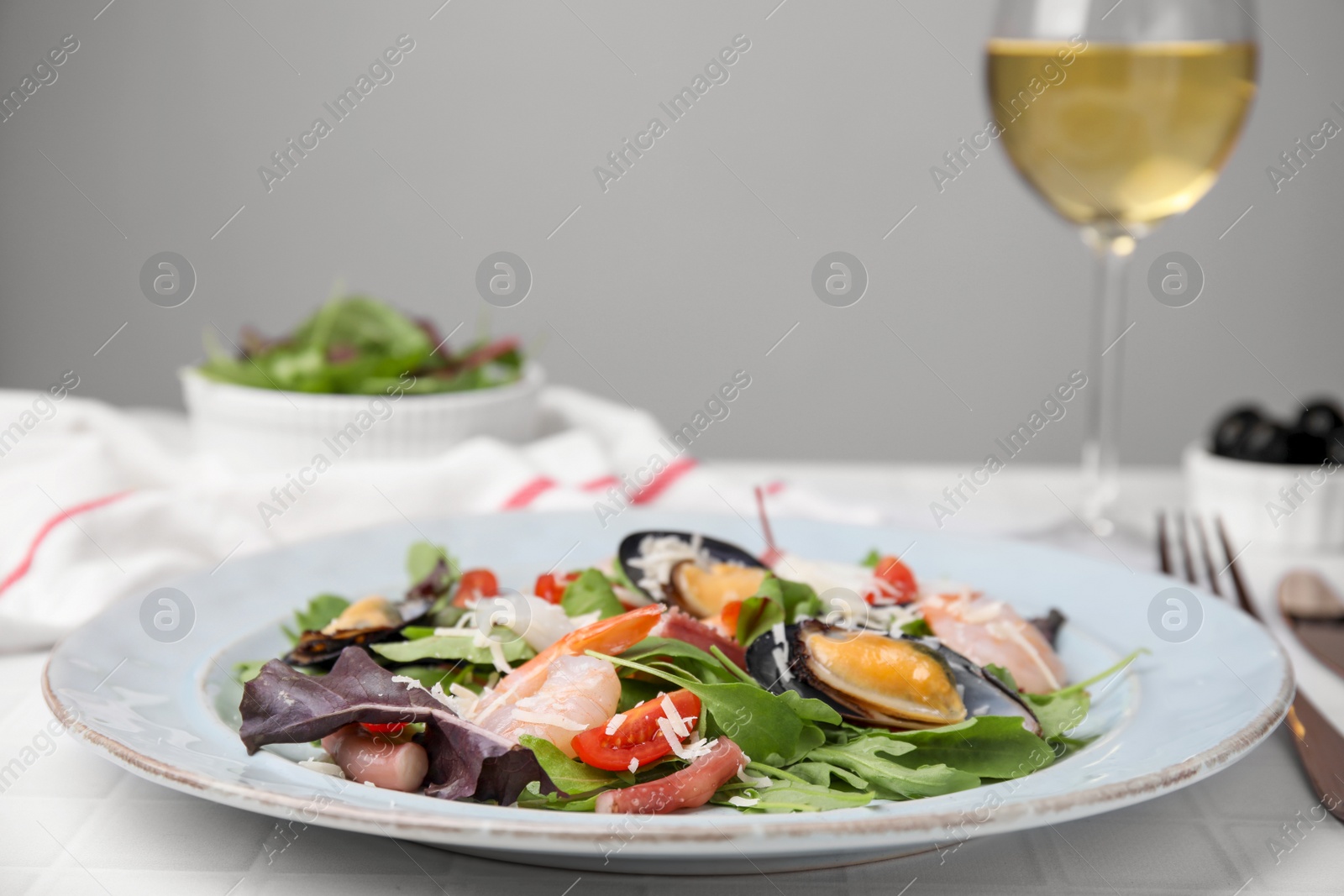 Photo of Plate of delicious salad with seafood on white tiled table