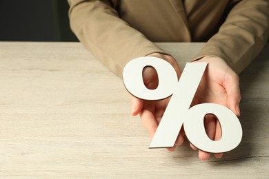 Photo of Woman holding percent sign at wooden table, closeup. Space for text