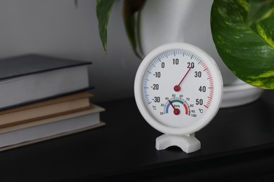 Photo of Round mechanical hygrometer on black shelf. Space for text