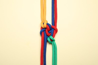 Photo of Colorful ropes tied together on beige background, top view. Unity concept