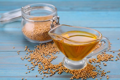 Photo of Jug of natural oil and mustard seeds on light blue wooden table