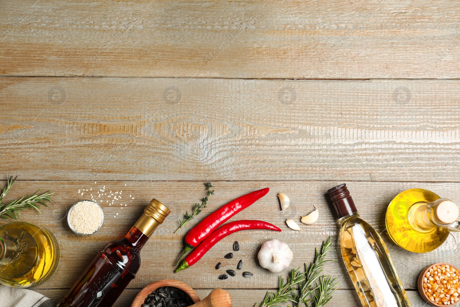 Photo of Flat lay composition with different sorts of cooking oil on wooden table. Space for text