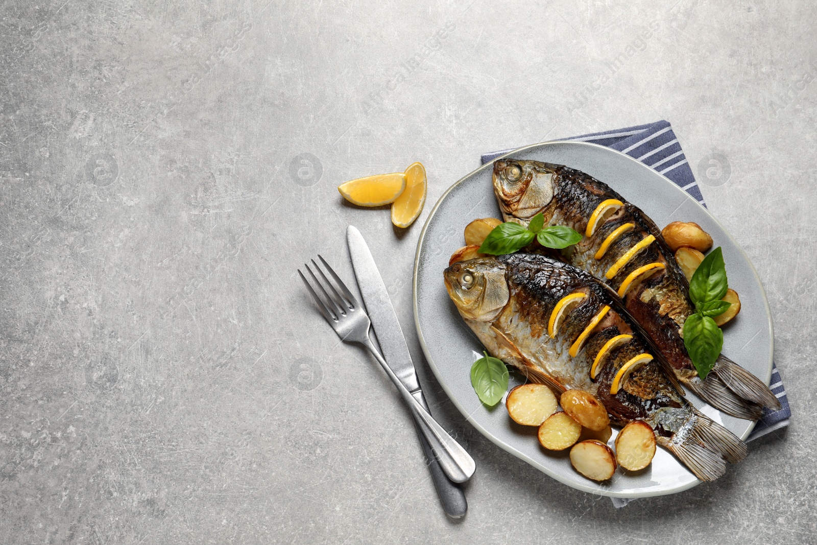 Photo of Tasty homemade roasted crucian carps served on light grey table, flat lay and space for text. River fish