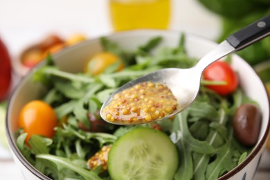 Photo of Spoon with tasty vinegar based sauce (Vinaigrette) over salad, closeup