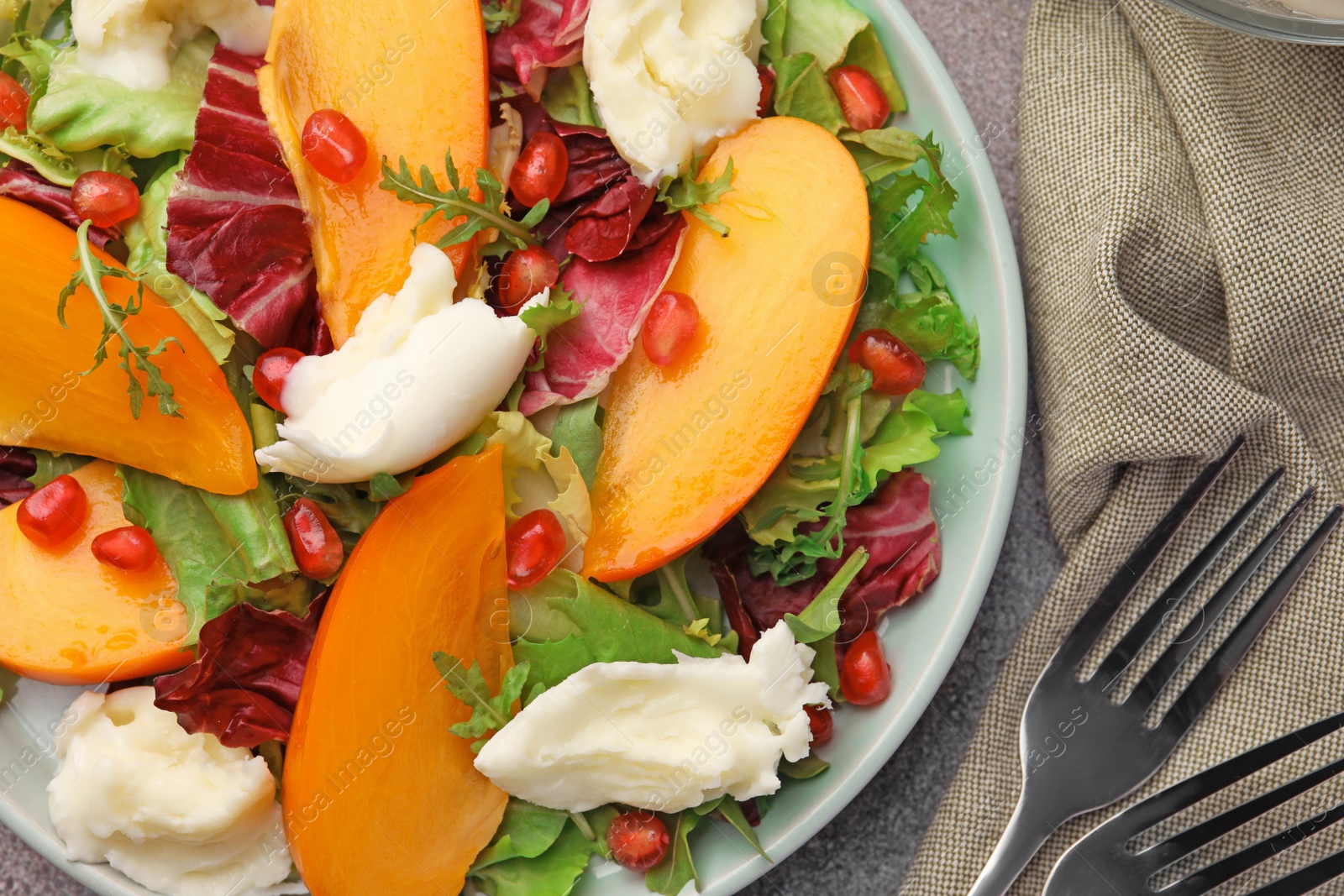 Photo of Delicious persimmon salad with cheese and pomegranate on cloth, flat lay