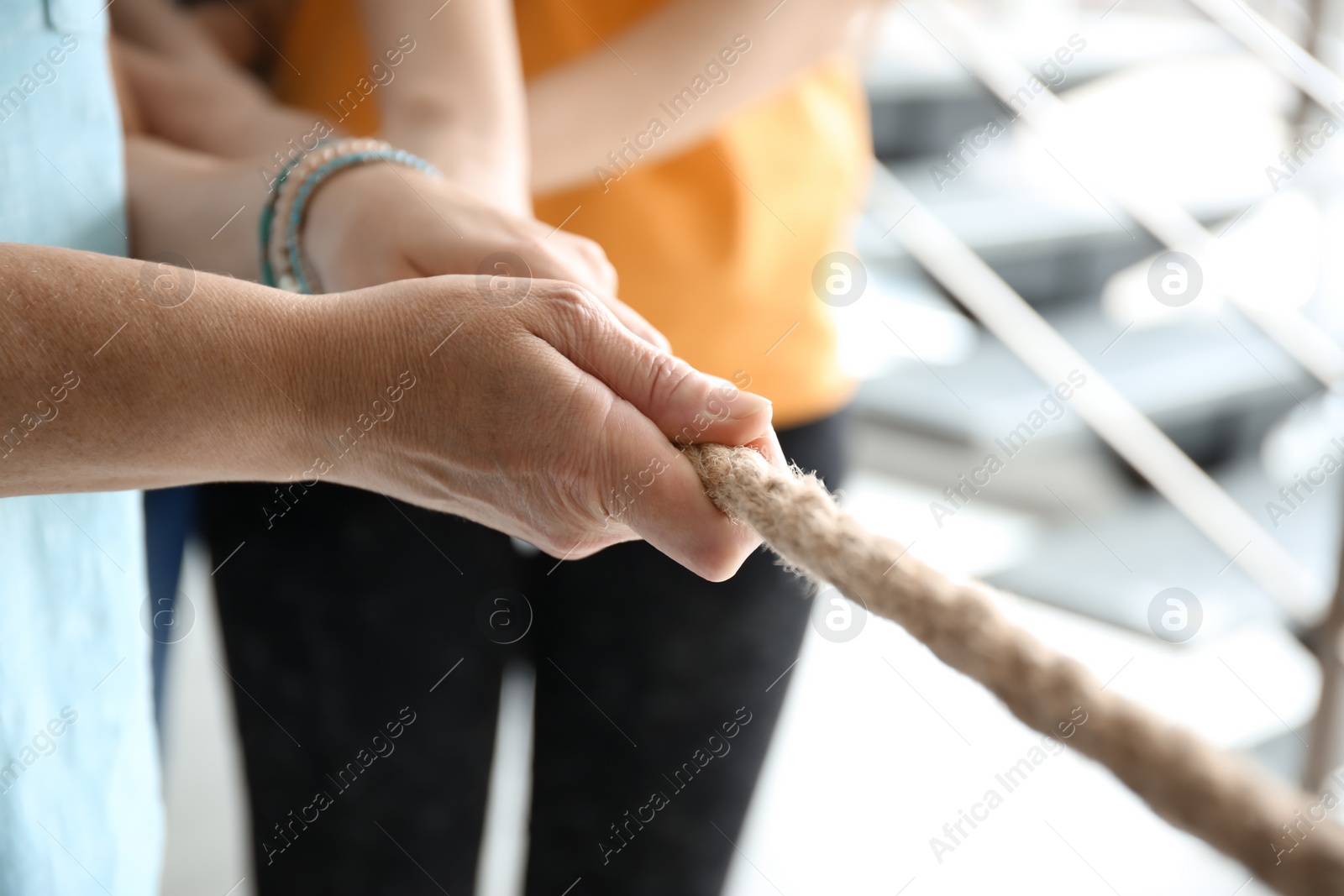 Photo of People pulling rope together, closeup of hands. Unity concept