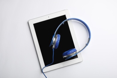 Photo of Stylish headphones and modern tablet on white background, top view