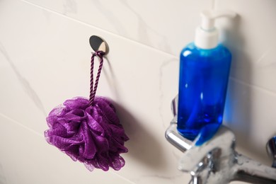 Purple shower puff and bottle of body wash gel in bathroom