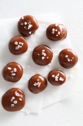 Tasty caramel candies and salt on white table, top view
