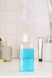 Photo of Bottle of mouthwash on white table in bathroom