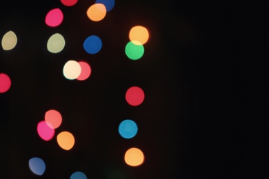 Blurred view of colorful lights on black background, space for text