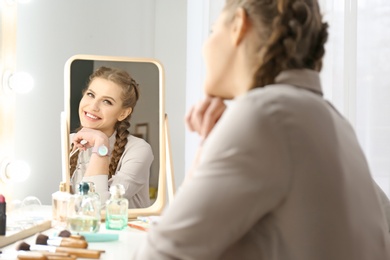 Photo of Portrait of beautiful woman with natural makeup near mirror indoors