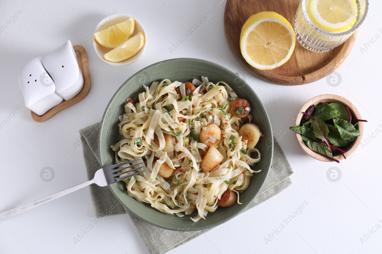 Photo of Delicious scallop pasta with spices in bowl served on white table, flat lay