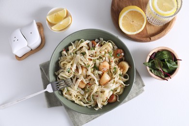 Delicious scallop pasta with spices in bowl served on white table, flat lay