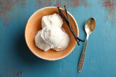 Photo of Bowl with tasty vanilla ice cream on wooden background