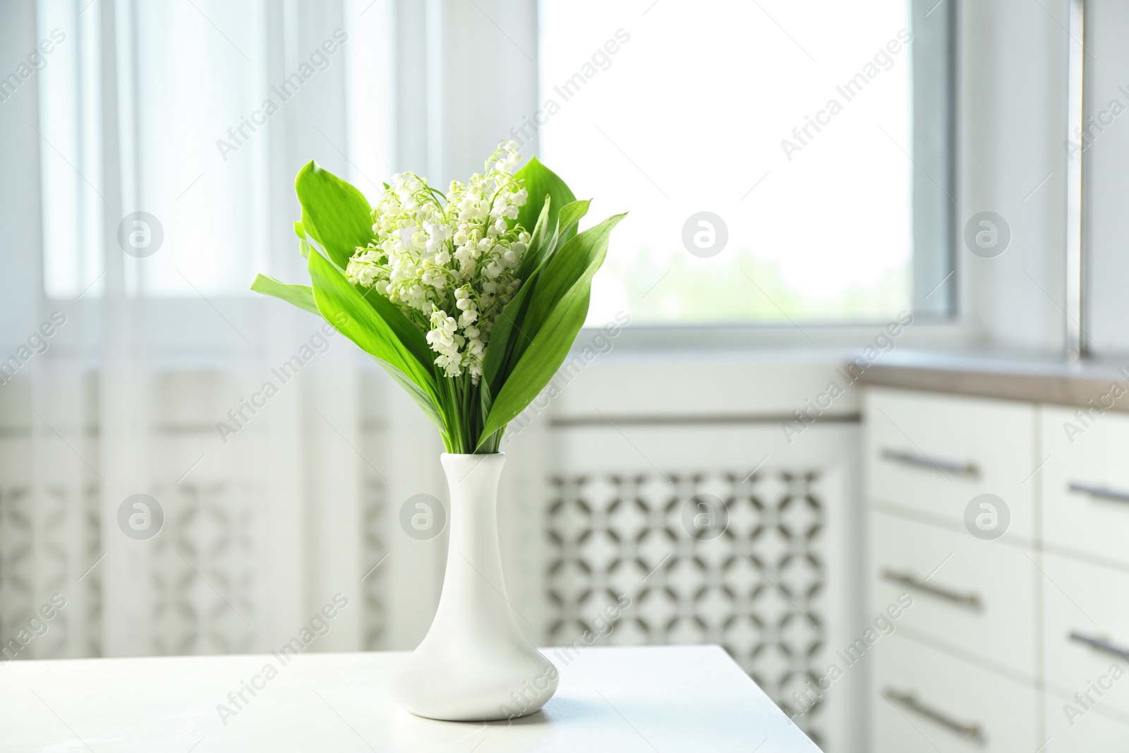 Photo of Vase with beautiful lily of the valley bouquet on table in room, space for text