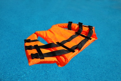 Bright orange life jacket floating in swimming pool