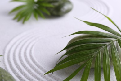 Photo of Zen concept. Stones, leaves and pattern on white sand, closeup. Space for text