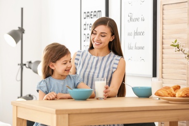 Photo of Mother and daughter having breakfast with milk at table