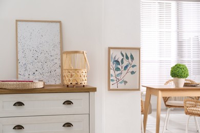 Photo of Stylish wicker holder with candle on chest of drawers indoors