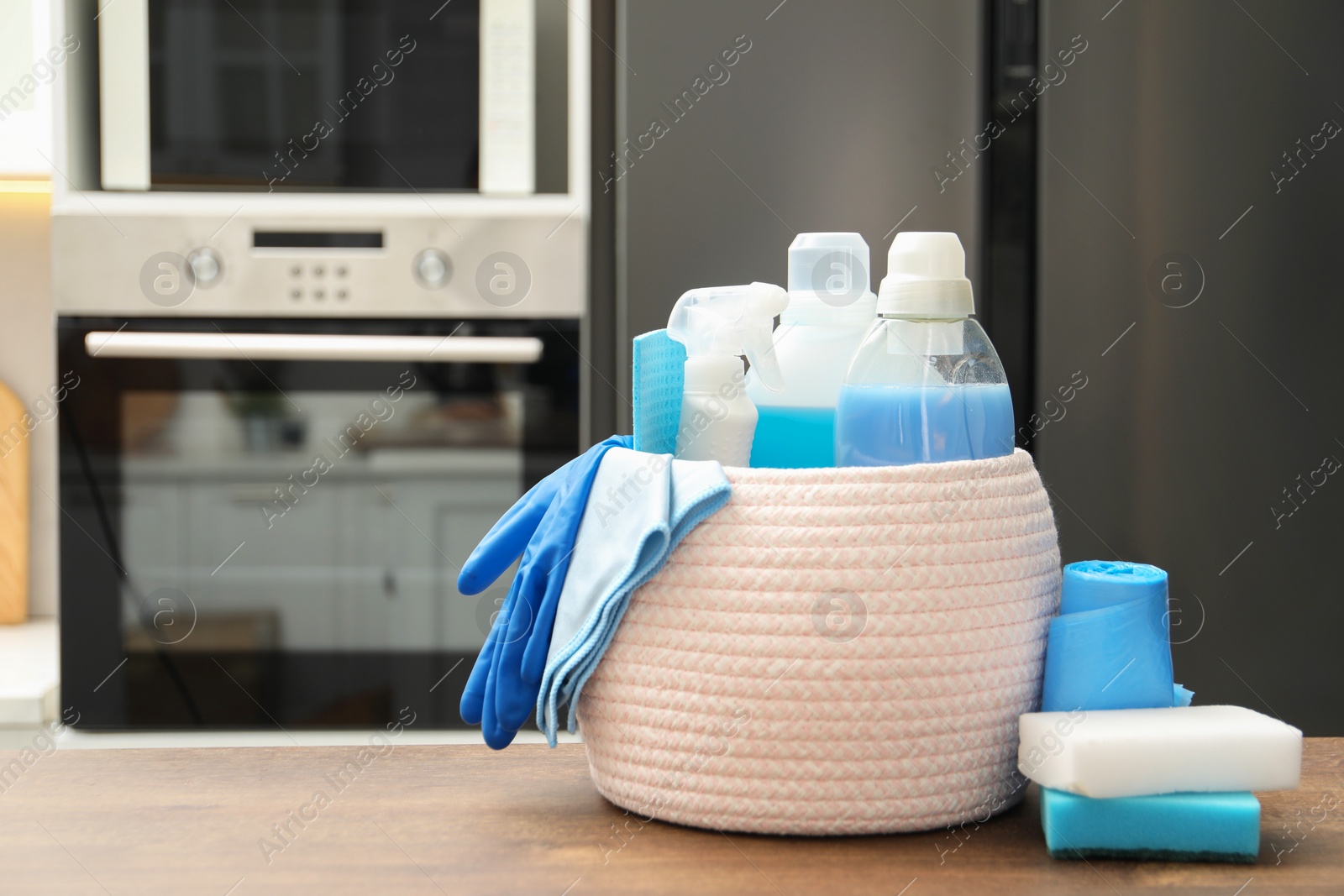 Photo of Different cleaning supplies in basket on table