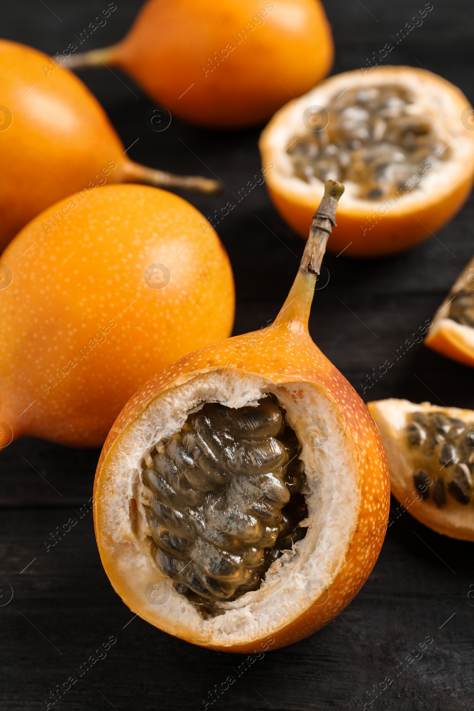 Photo of Delicious ripe granadillas on black wooden table, closeup