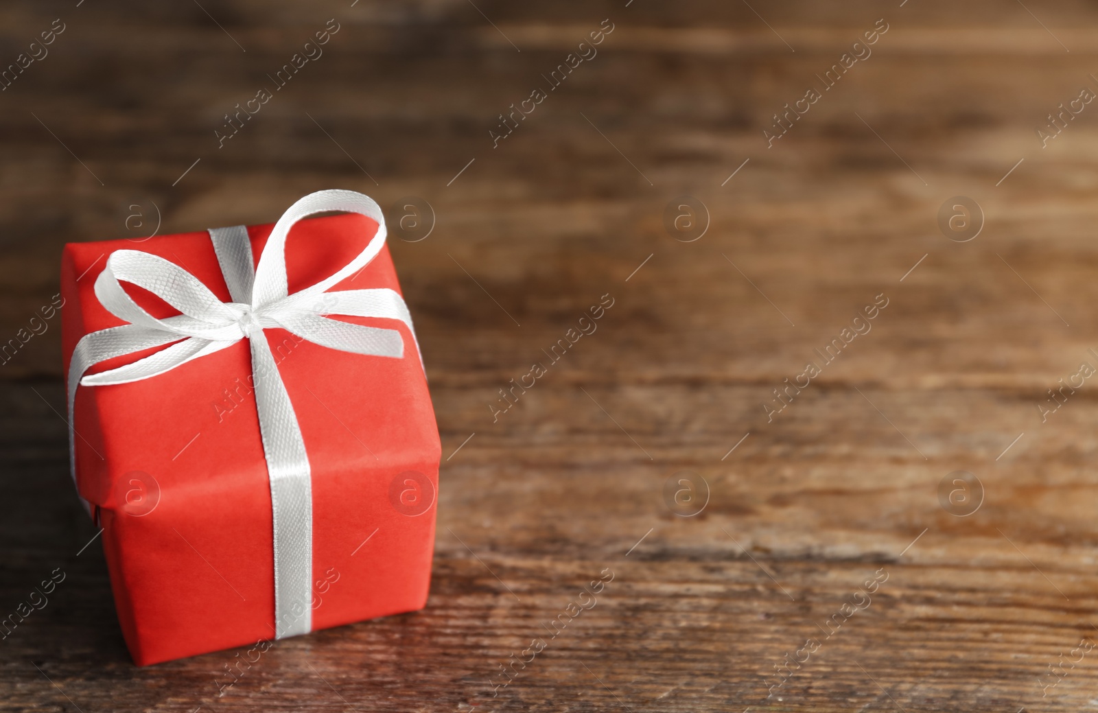 Photo of Beautiful gift box on wooden table, closeup. Space for text