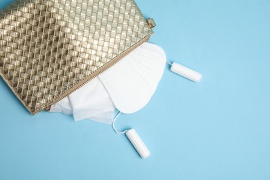 Photo of Bag with menstrual pads, tampons and pantyliners on light blue background, flat lay