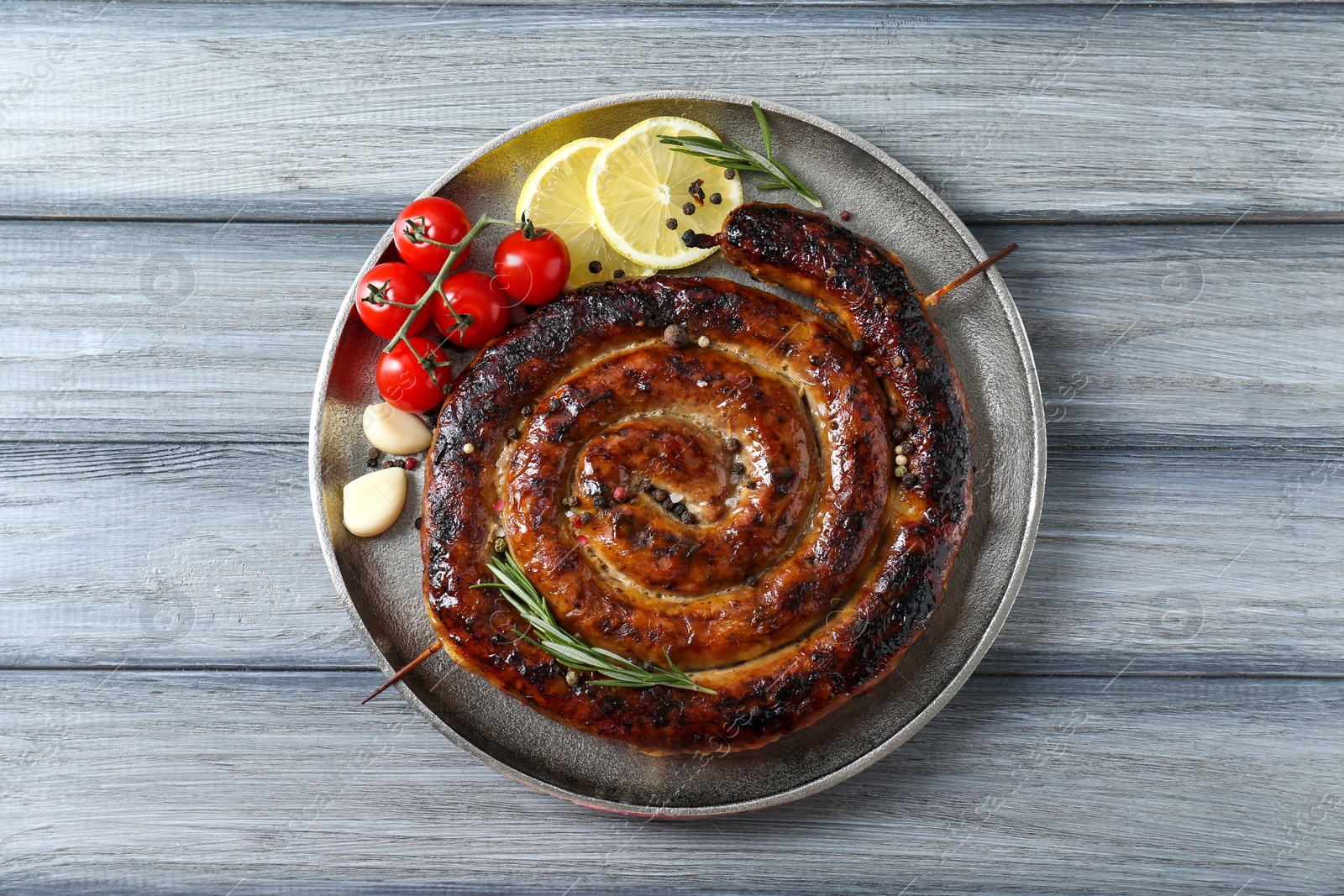 Photo of Delicious homemade sausage with spices, tomatoes and lemon on light grey wooden table, top view