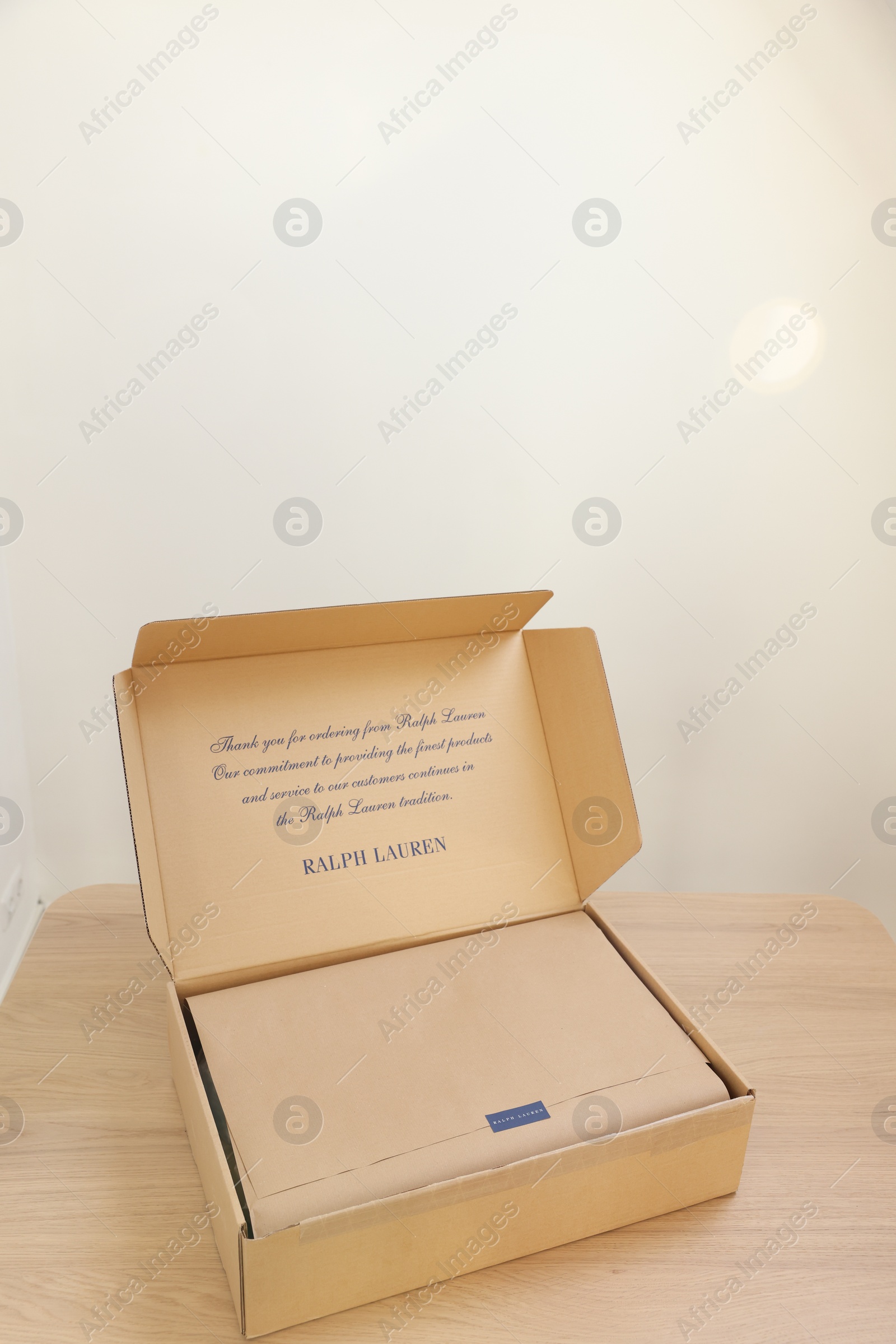Photo of Leiden, Netherlands - December 6, 2023: Open box with Ralph Lauren garment on wooden table