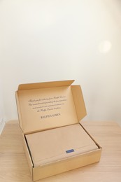 Photo of Leiden, Netherlands - December 6, 2023: Open box with Ralph Lauren garment on wooden table