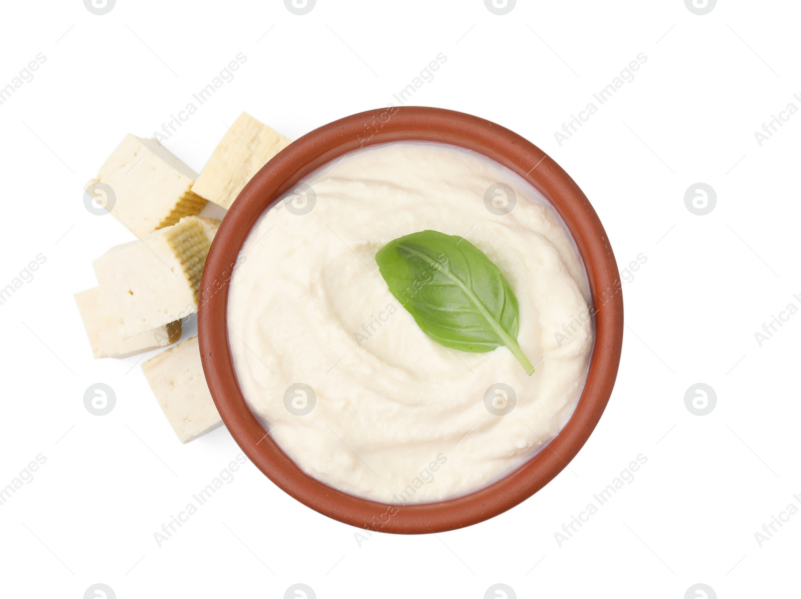 Photo of Delicious tofu, sauce and basil leaf in bowl isolated on white, top view