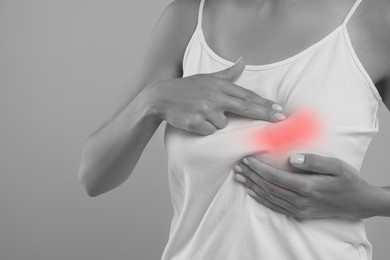 Image of Woman doing breast self-examination on grey background, closeup. Color accent effect