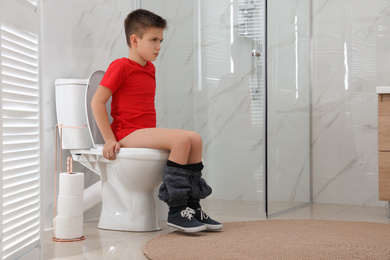 Photo of Boy suffering from hemorrhoid on toilet bowl in rest room