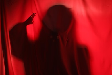 Silhouette of creepy ghost behind red cloth