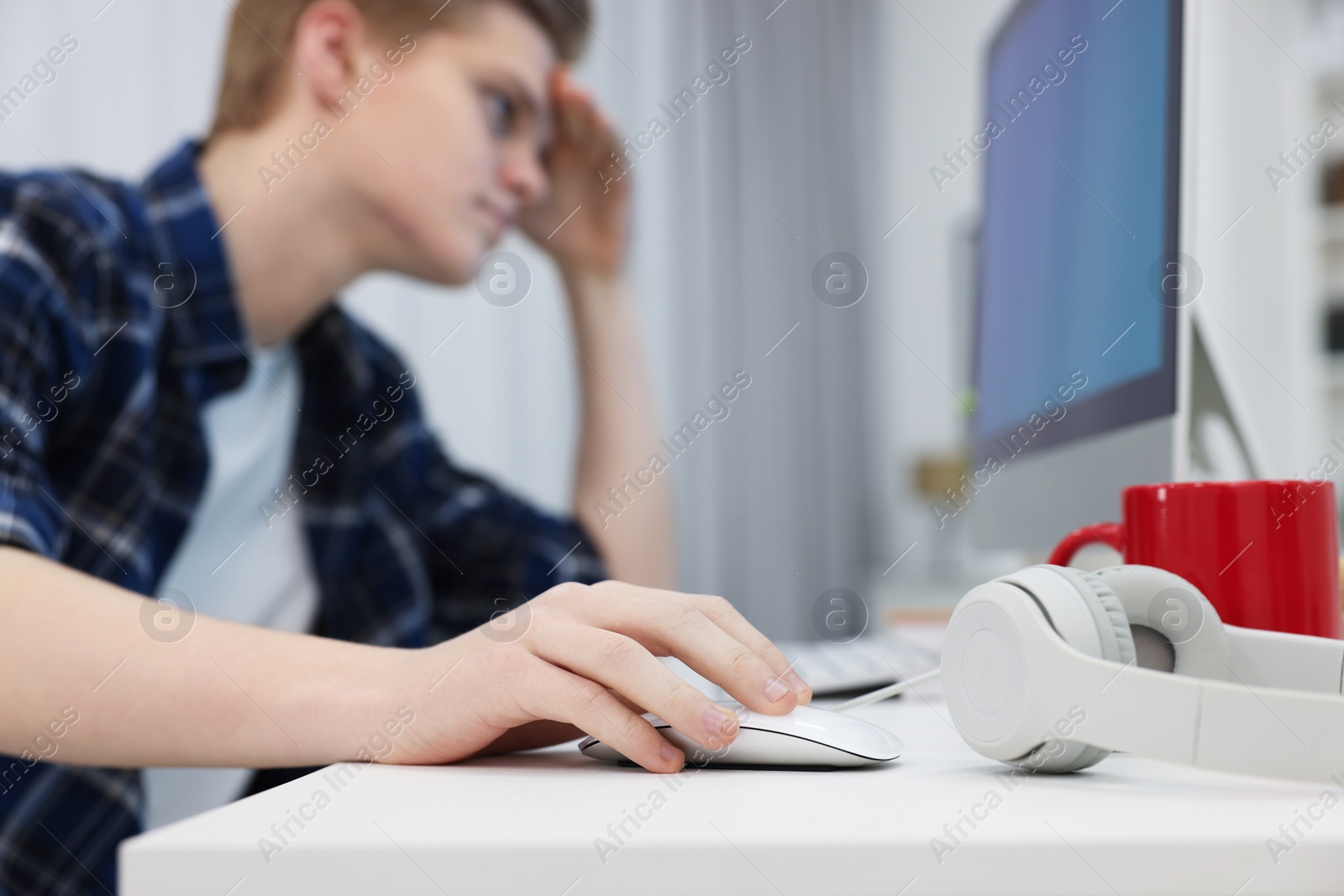 Photo of Teenage boy using computer in room, focus on hand. Internet addiction