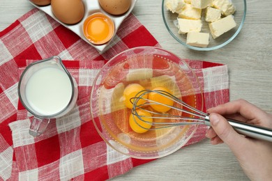Photo of Woman whisking eggs at white wooden table, top view