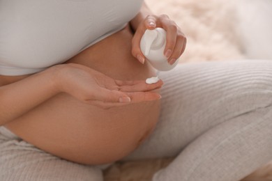 Young pregnant woman with cosmetic product on floor, closeup