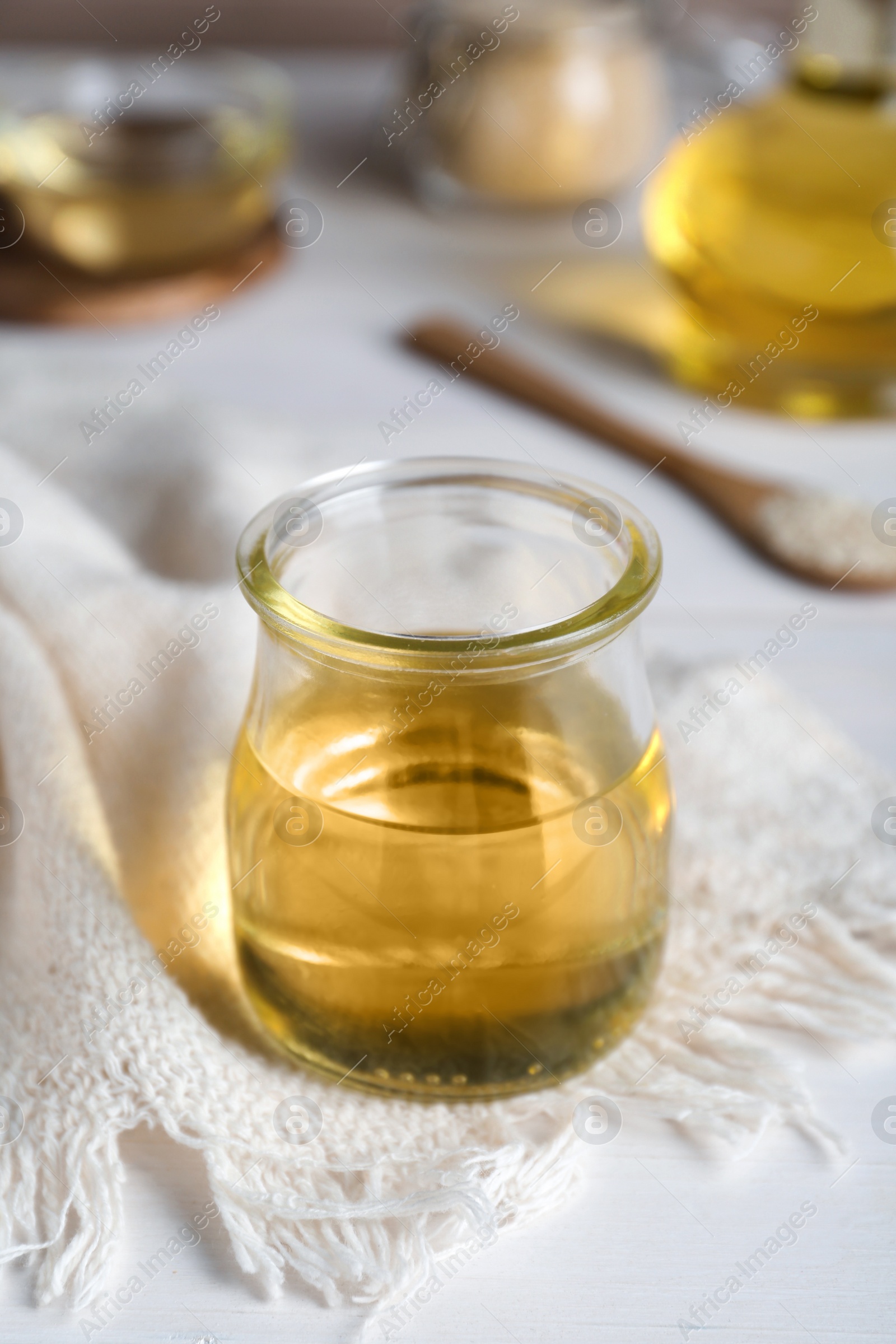 Photo of Jar of organic sesame oil on white wooden table, closeup