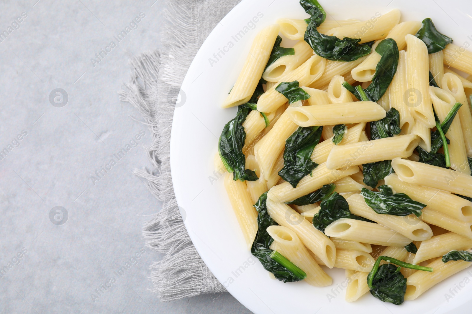 Photo of Tasty pasta with spinach and sauce on grey table, top view. Space for text