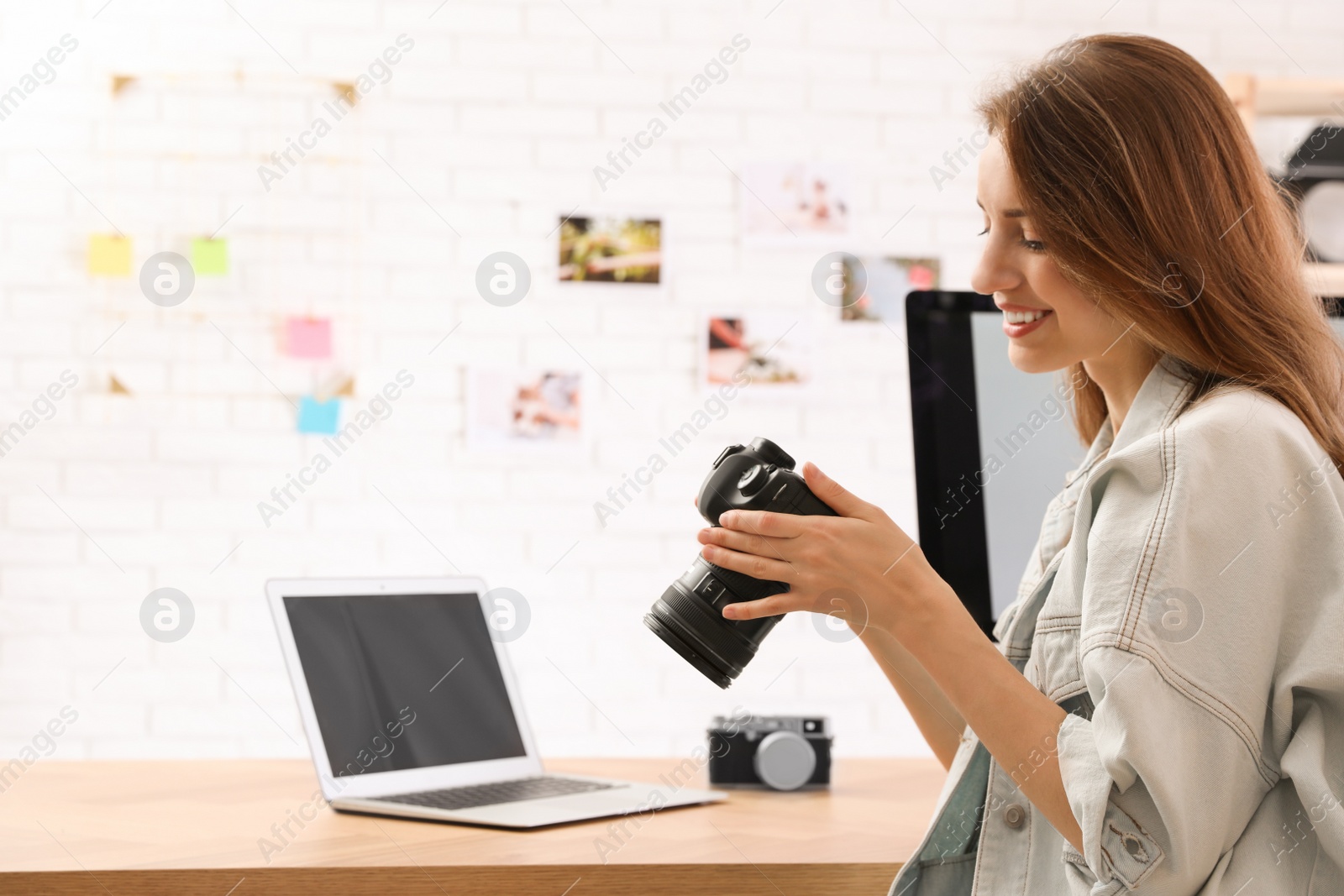 Photo of Professional photographer with camera working at table in office