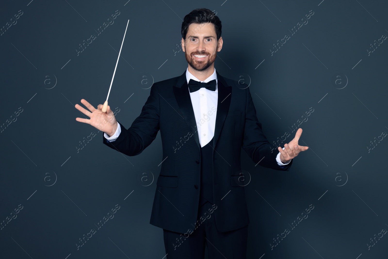 Photo of Happy professional conductor with baton on grey background